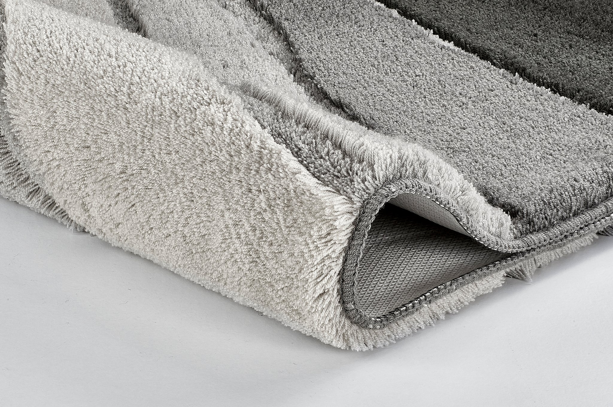Nahaufnahme einer gefalteten, grau gestreiften Badematte aus Frottier