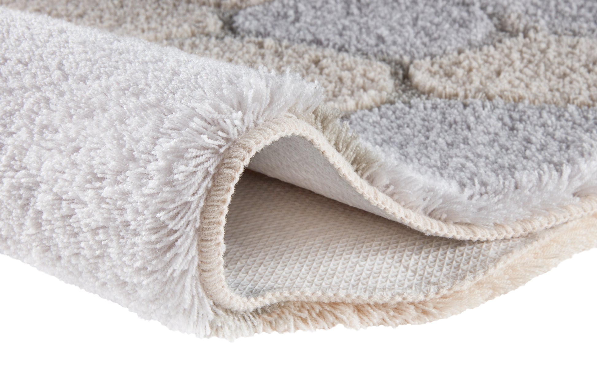 Der flauschige Teppich in Creme und Grau zeigt seine weiche Hochflorstruktur.