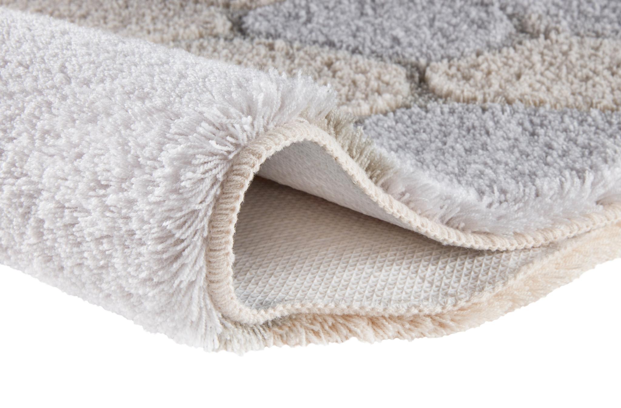 Der flauschige Teppich in Creme und Grau zeigt seine weiche Hochflorstruktur.