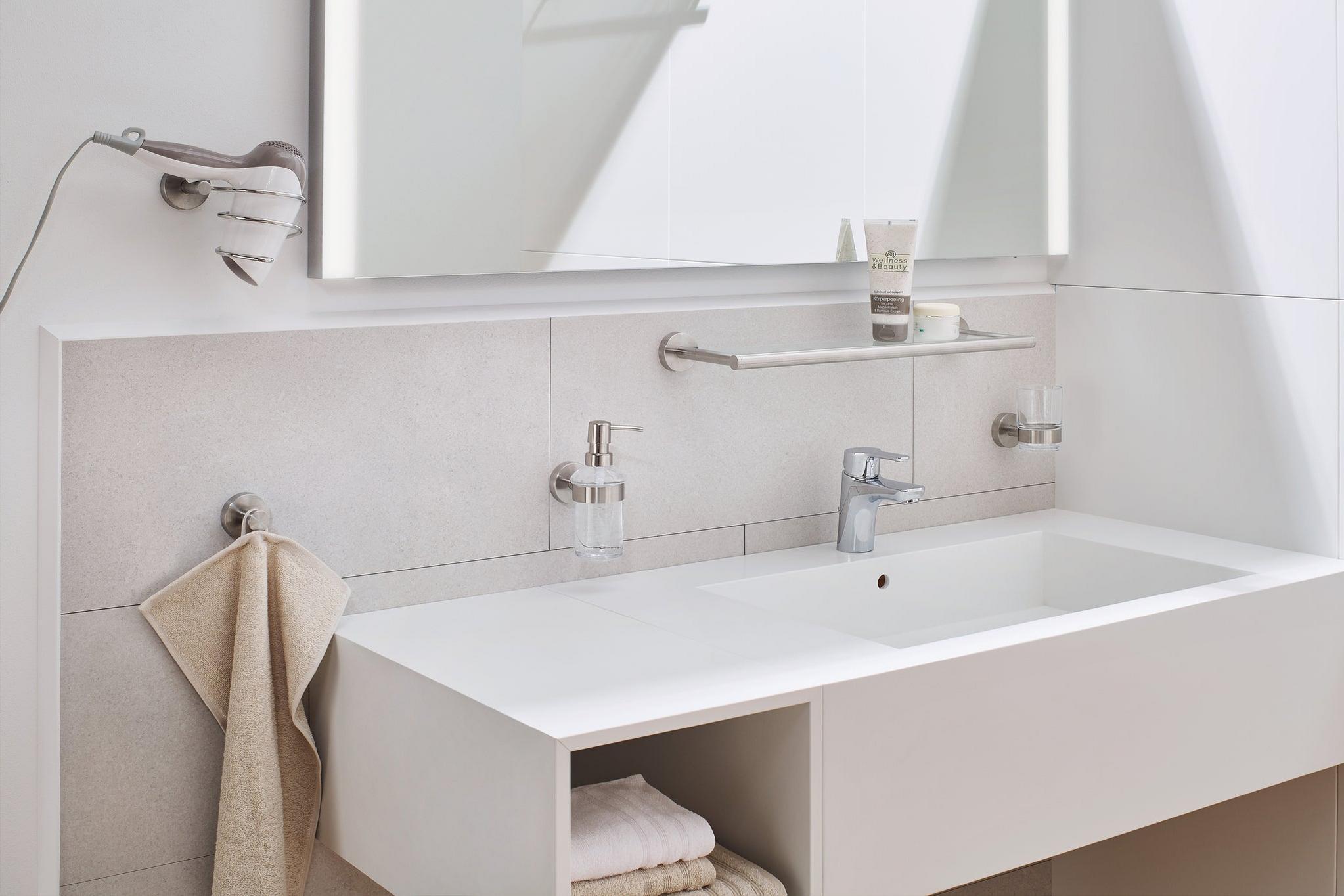 Modernes weißes Waschbecken mit Handtuch und Badaccessoires
