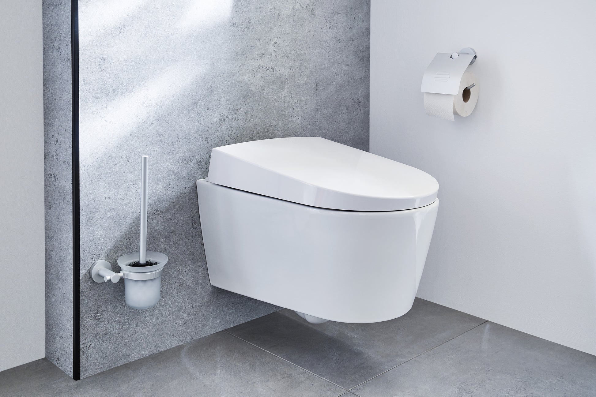 Wand-WC-Bürstenhalter APOLLO Milky neben wandhängendem WC in modernem Bad aus Fliesen.