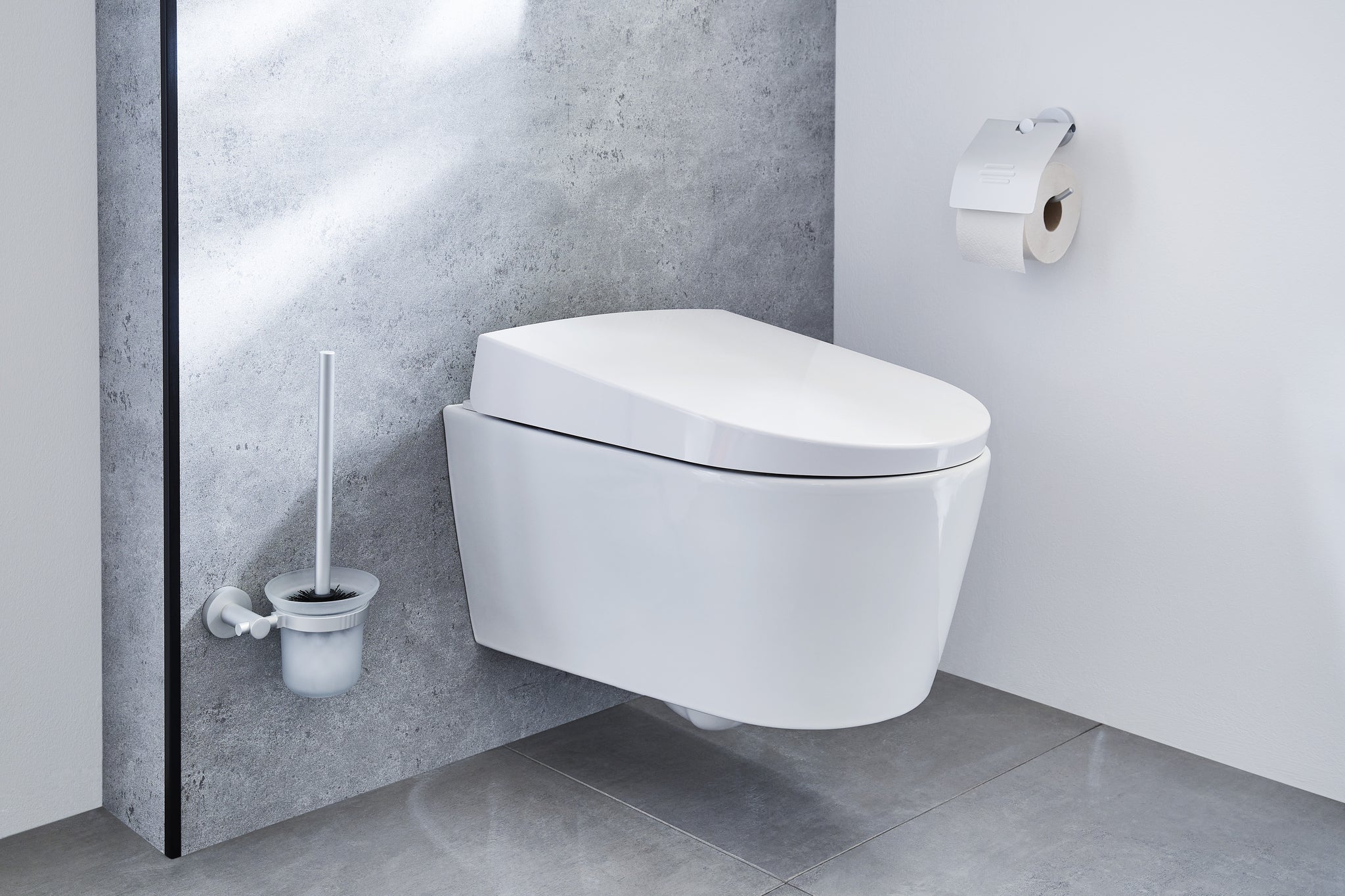 Wand-WC-Bürstenhalter APOLLO Milky neben wandhängendem WC in modernem Bad aus Fliesen.