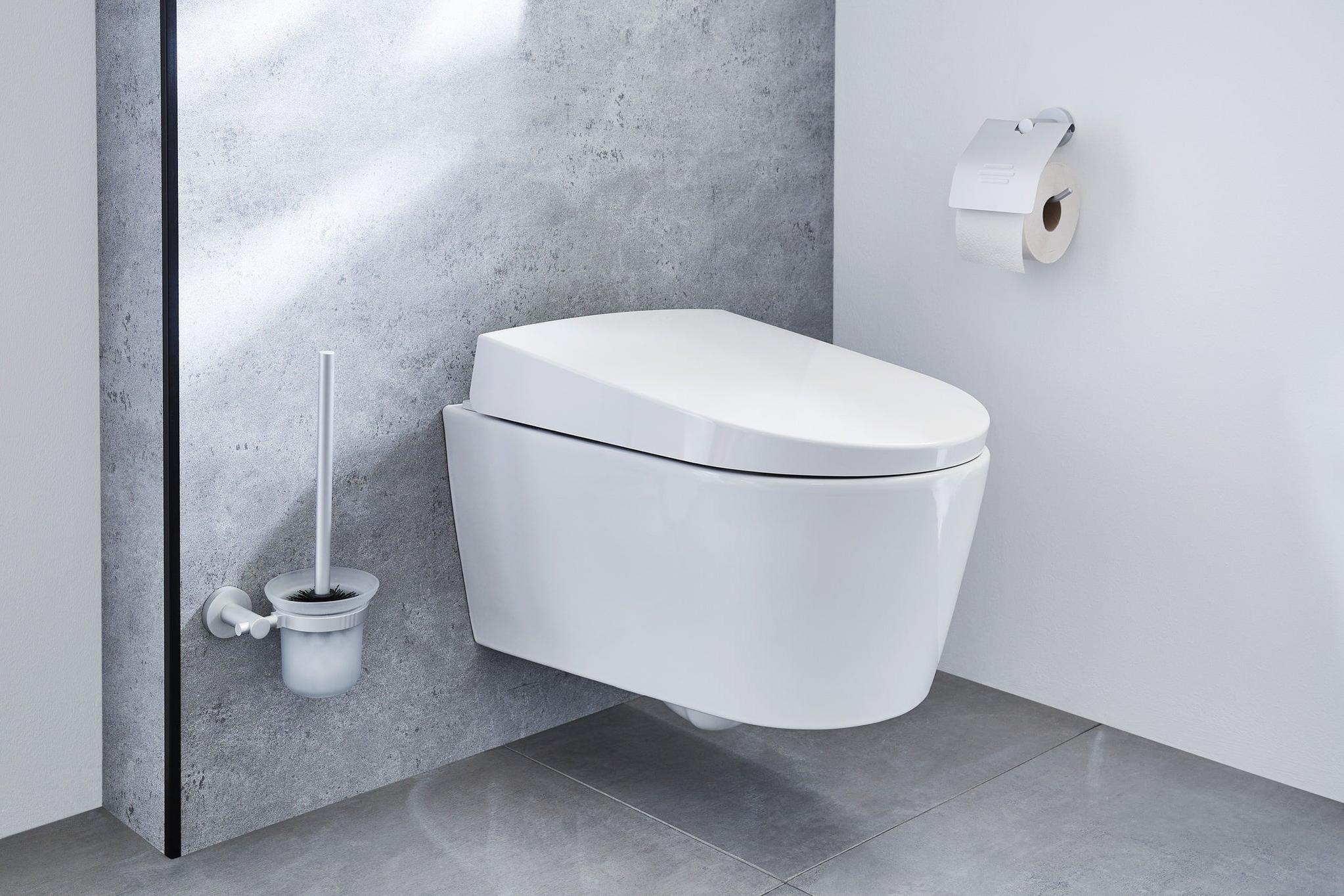 Wandhängendes WC in Weiß mit Toilettenbürste und Papierhalter daneben