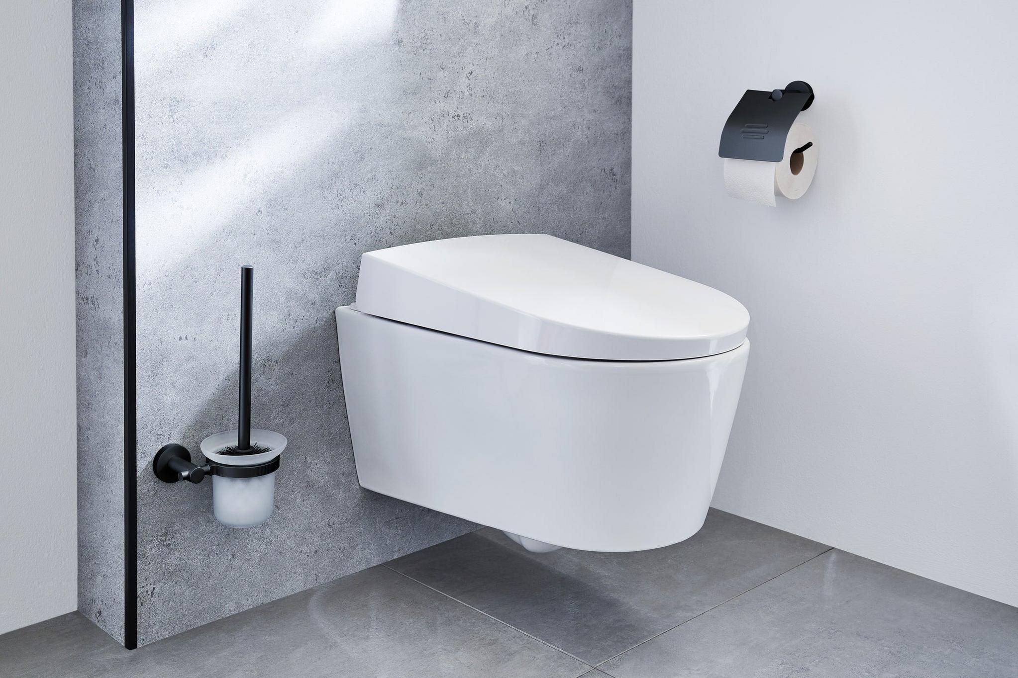 Wandhängendes weißes WC mit WC-Bürste und schwarzem Toilettenpapierhalter