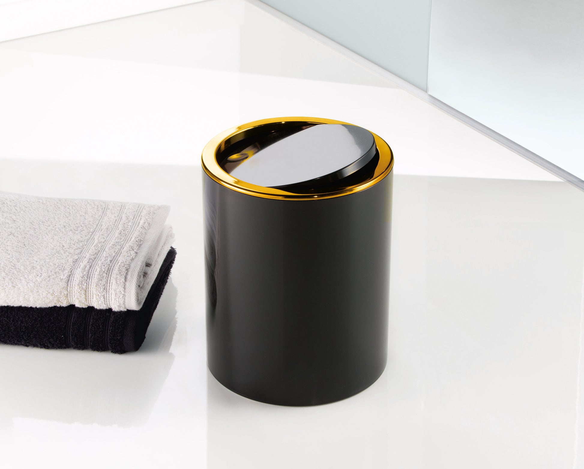 Kosmetikeimer GOLDEN CLAP Schwarz 5 Liter steht neben gefalteten Handtüchern im Bad.