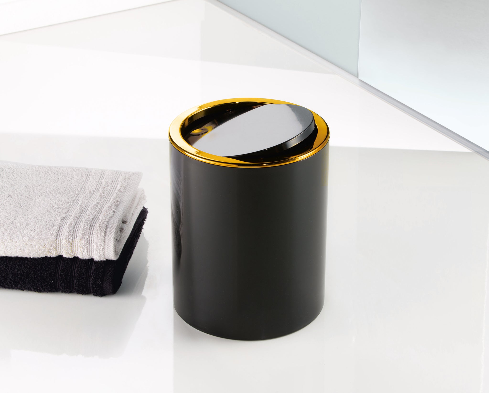 Kosmetikeimer GOLDEN CLAP Schwarz 5 Liter steht neben gefalteten Handtüchern im Bad.