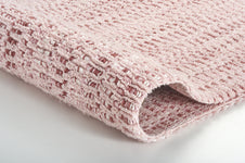 Gefaltete rosafarbene Badematte mit strukturierter Waffeloberfläche