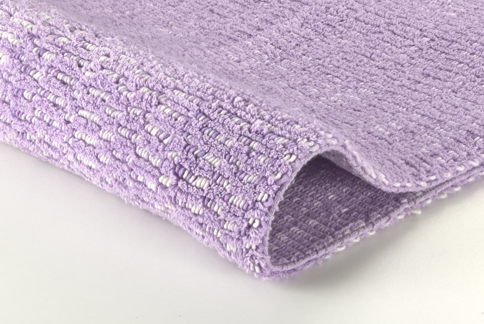 Nahaufnahme eines fliederfarbenen, strukturierten Badezimmerteppichs