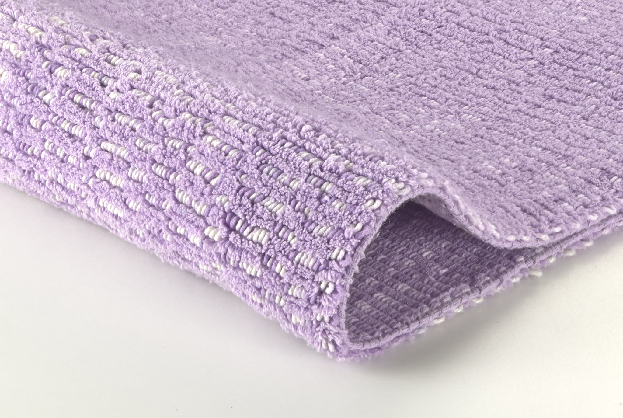 Nahaufnahme eines fliederfarbenen, strukturierten Badezimmerteppichs