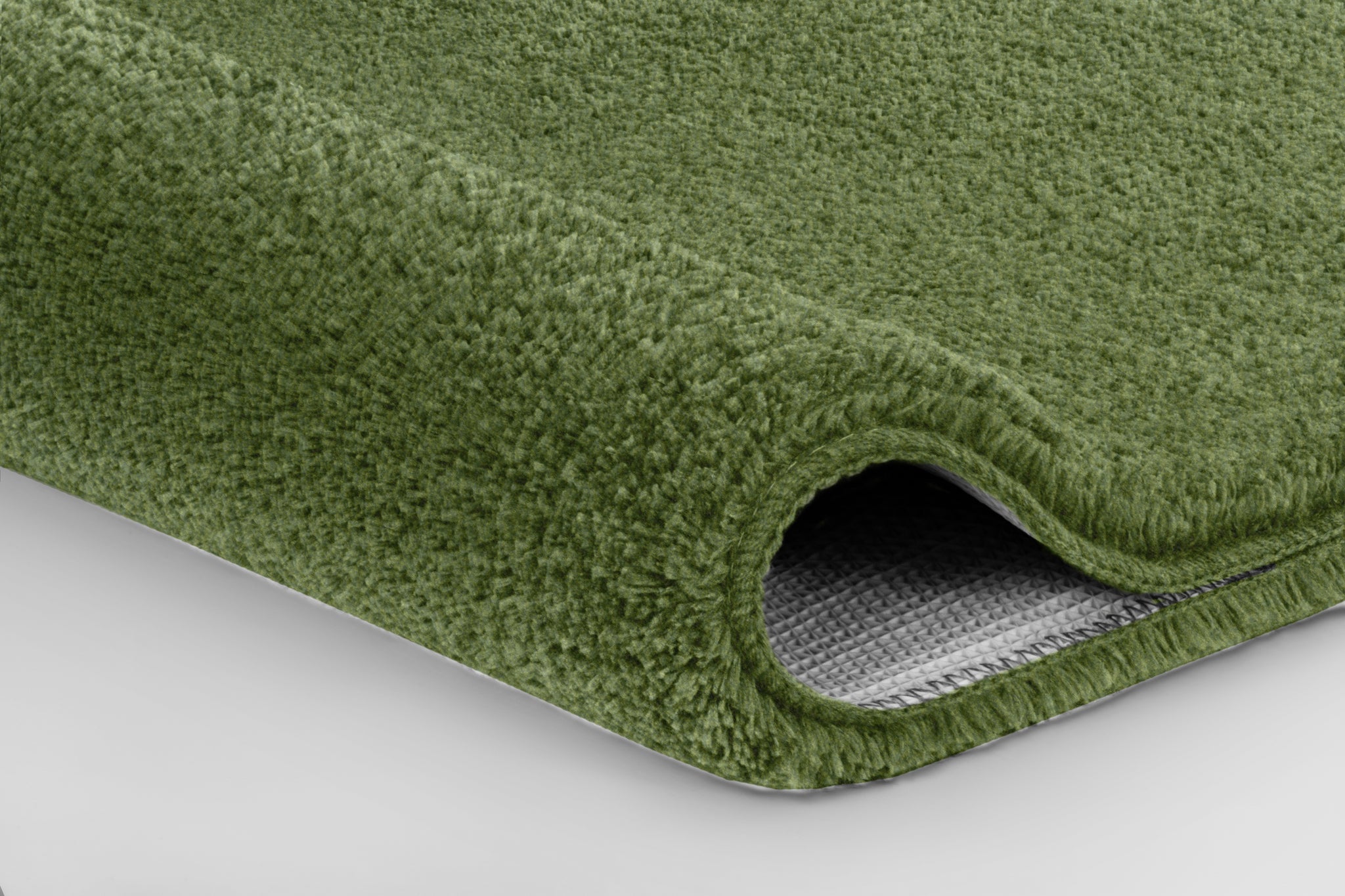 Nahaufnahme einer grünen Badematte mit umgeschlagener Ecke aus Stoff