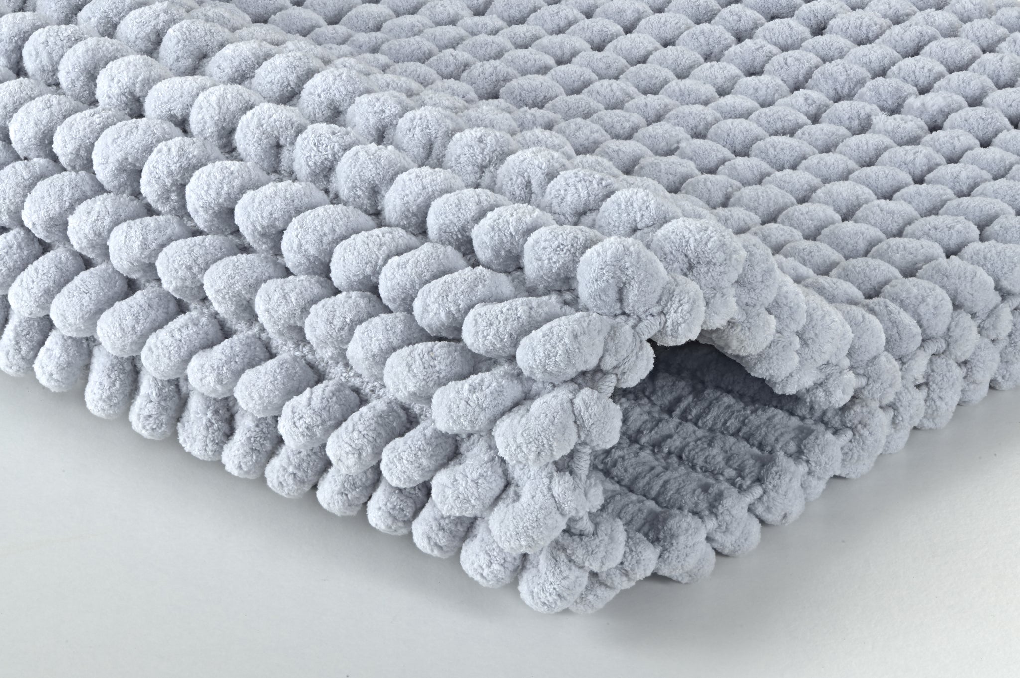 Nahaufnahme einer dicken, hellgrauen Chenille-Badematte mit Noppen
