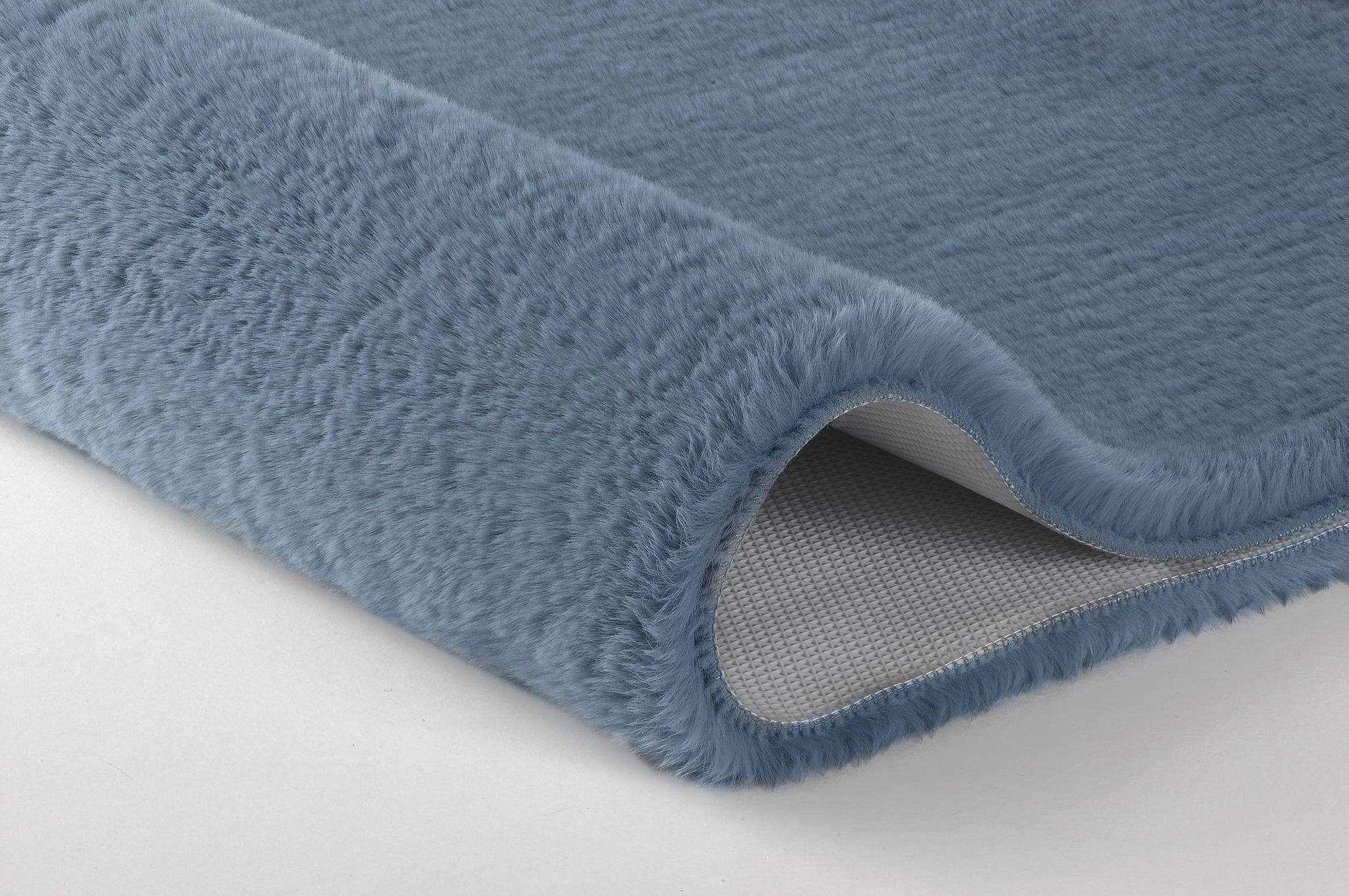 Detailansicht einer blauen, flauschigen Badematte mit abgerollter Kante