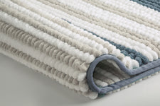 Nahaufnahme eines gestreiften Badteppichs in Weiß, Grau und Blau