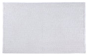 Weißer Badteppich CHRISSY in 60 x 100 cm liegt flach auf hellem Untergrund.