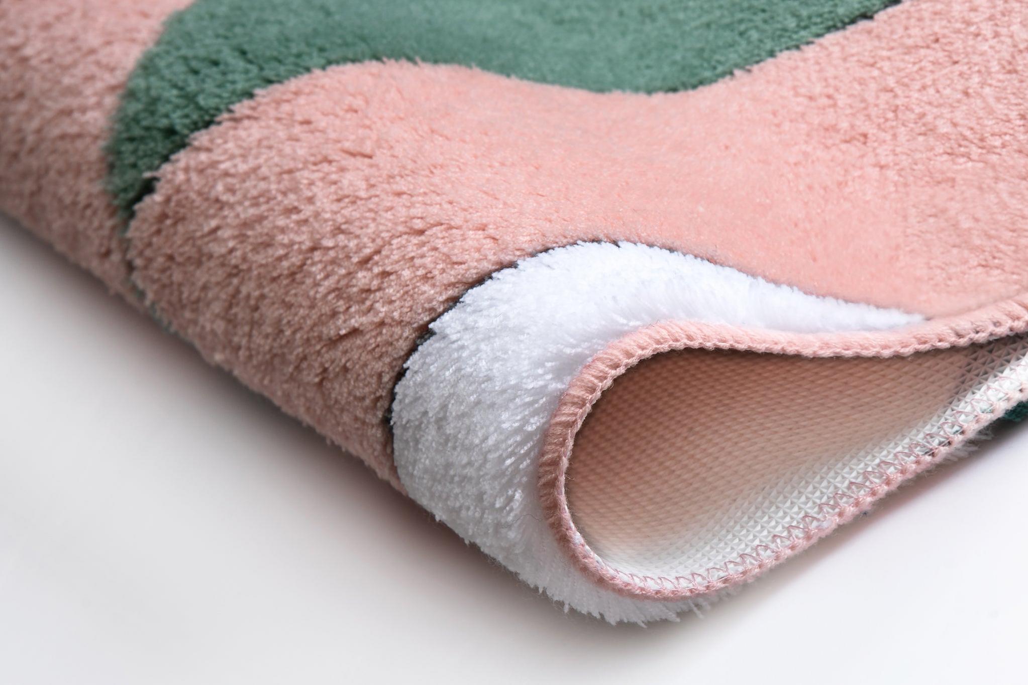 Nahaufnahme eines flauschigen Badematte-Rands in Rosa, Grün, Weiß