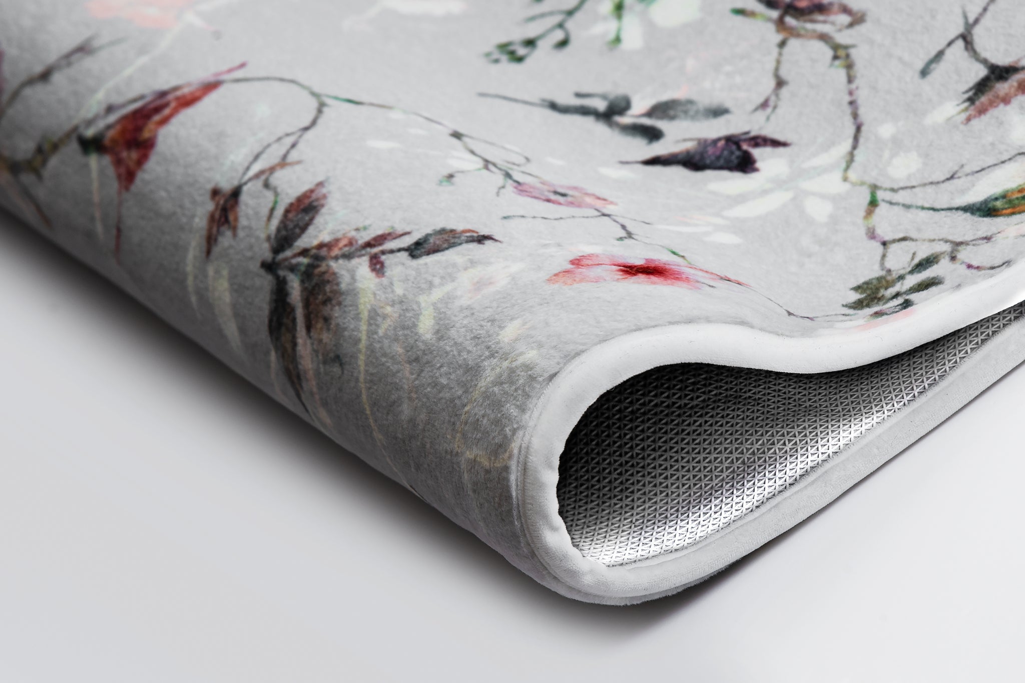 Nahaufnahme des Badteppichs FLORES Multicolor mit floralem Muster auf grauem Grund.