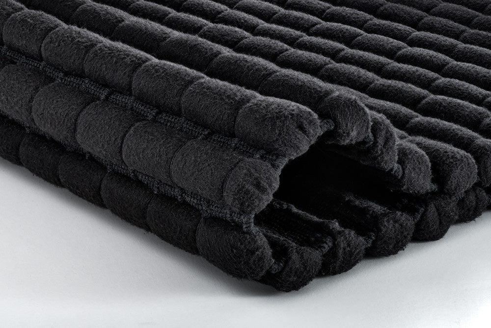 Gefaltete schwarze Badematte mit weicher, strukturierter Oberfläche