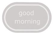 Ovaler hellgrauer Badteppich mit weißem Schriftzug good morning
