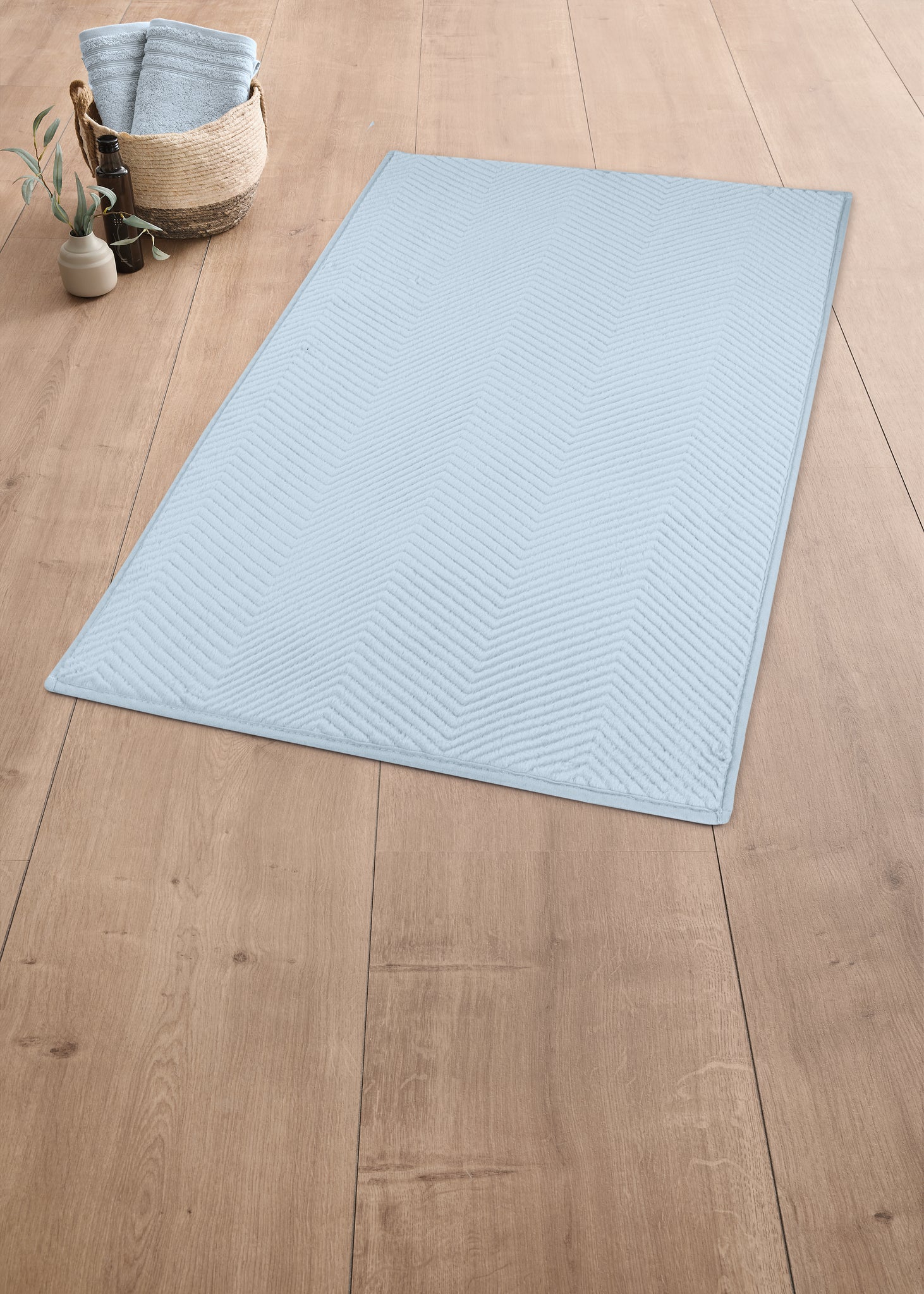 Hellblauer Badteppich mit Fischgrätenmuster auf Holzboden im Bad