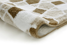 Nahaufnahme einer weichen Badematte mit beige-braunem Karomuster aus Stoff