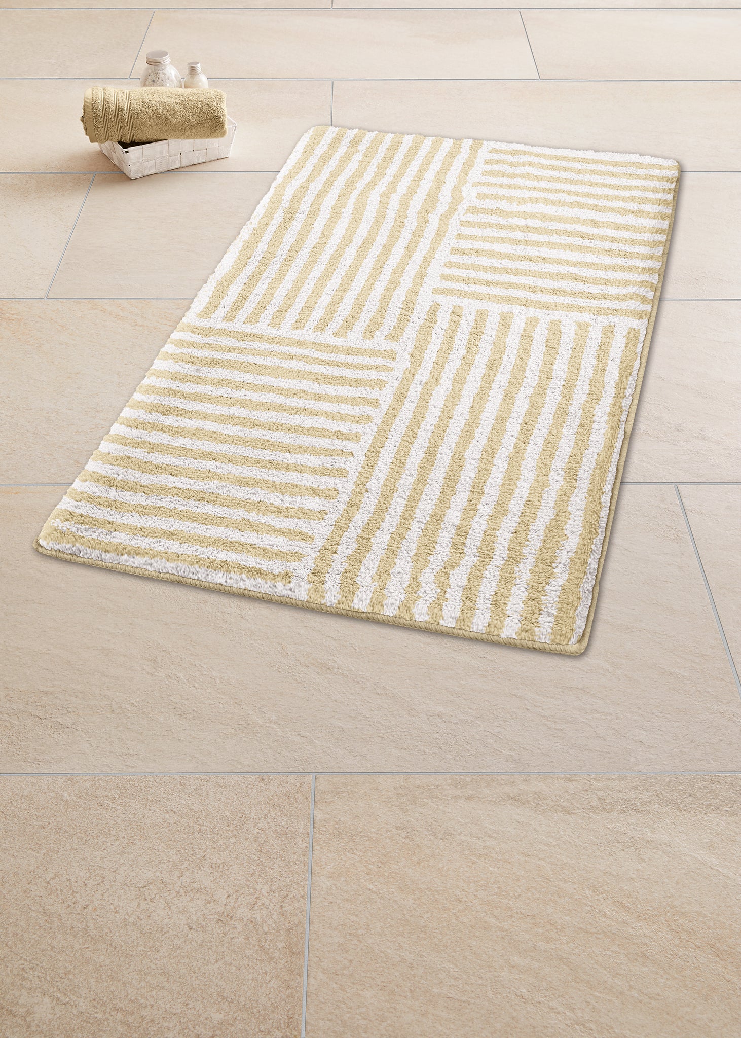 Badteppich CHELSEA Sandbeige 60 x 90 cm liegt mit Streifenmuster auf hellen Fliesen neben Handtüchern.