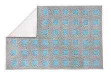 Grau-blauer Badteppich mit Karomuster, eine Ecke nach oben umgeschlagen