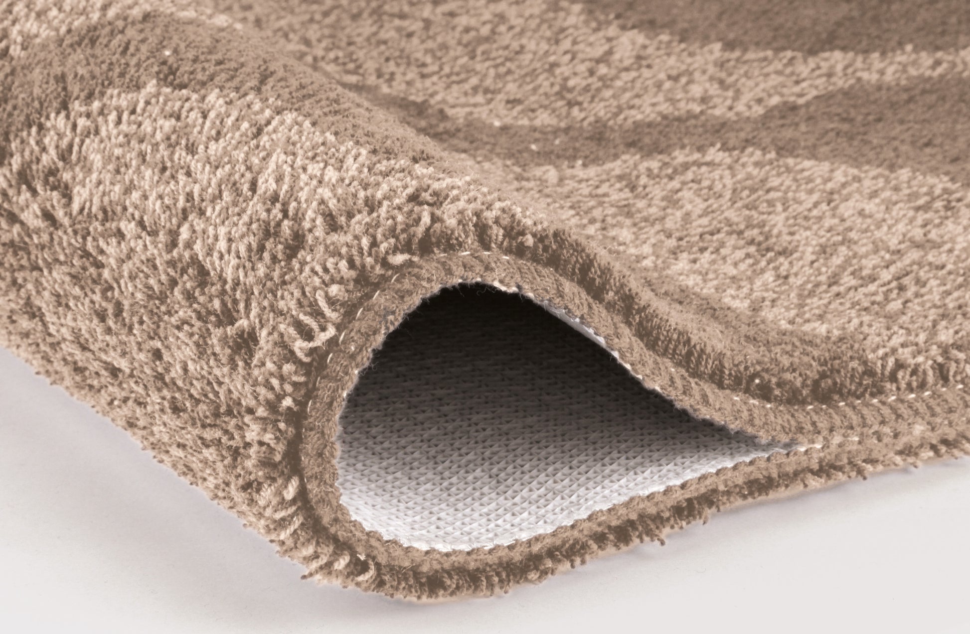 Nahaufnahme einer beigen Badematte mit weicher, dichter Schlingenstruktur