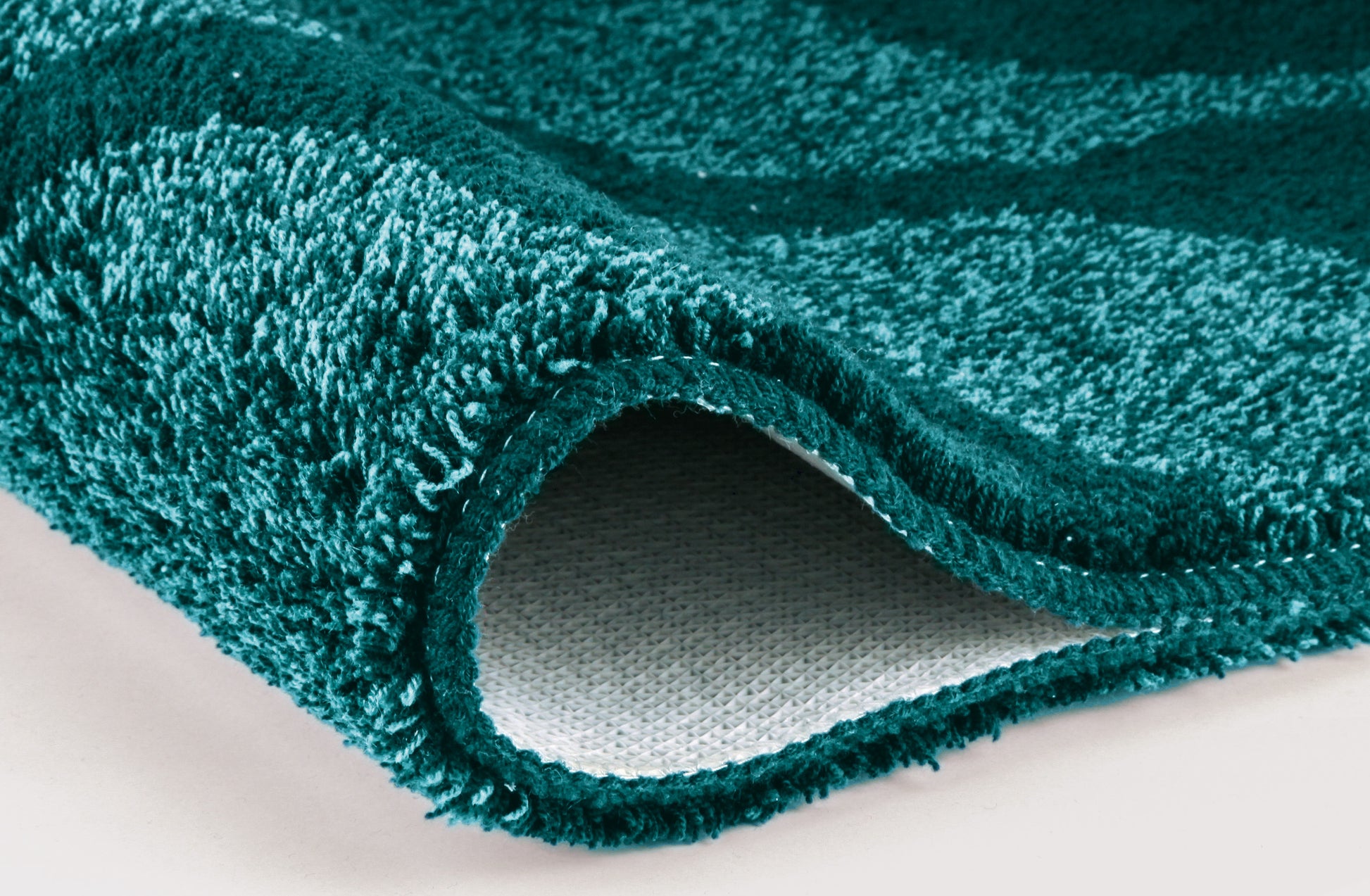 Nahaufnahme einer türkisgrünen Badematte mit rutschfester Rückseite