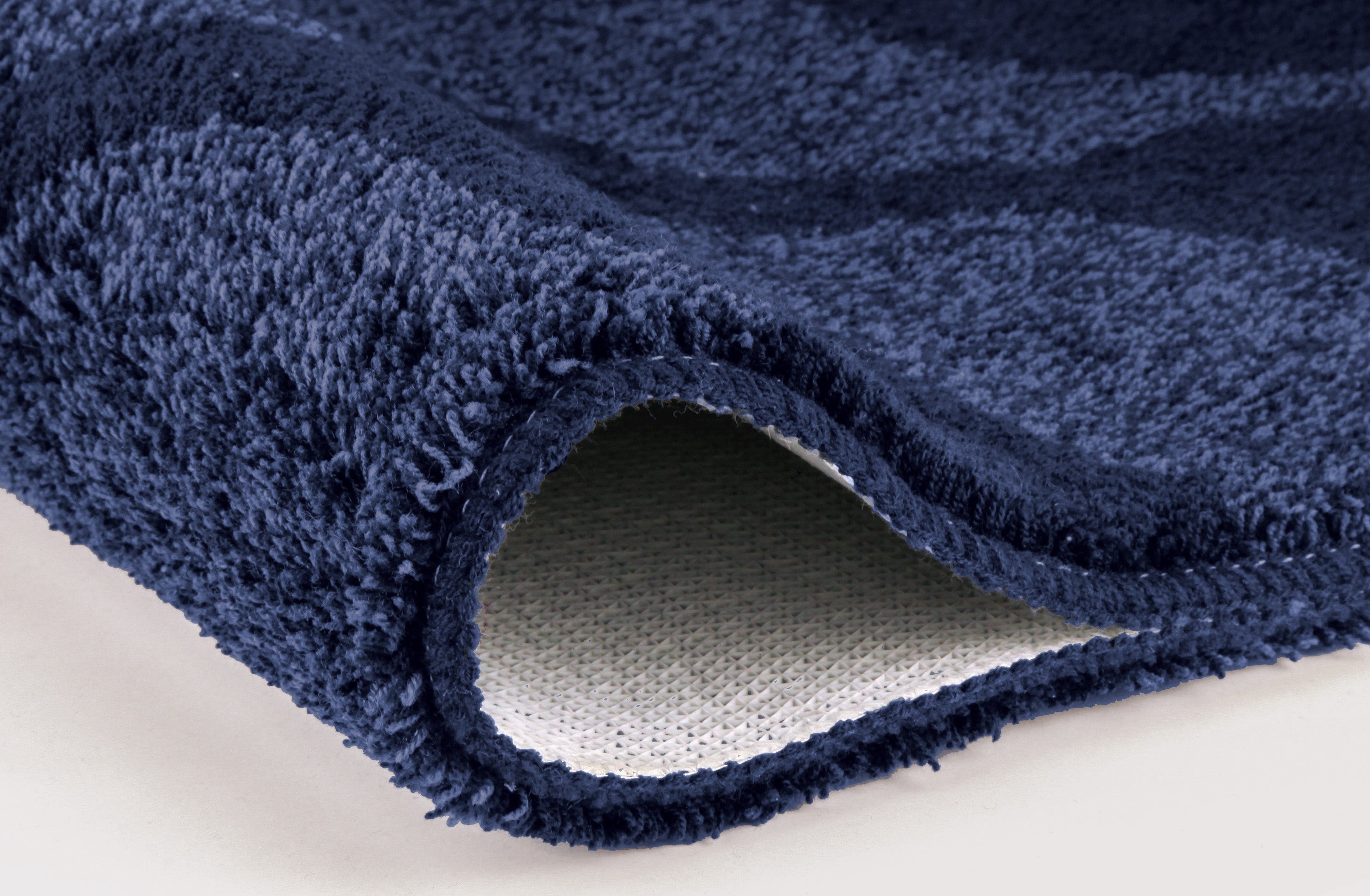 Nahaufnahme dunkelblaue Badematte, umgeschlagene Kante mit Rückseite
