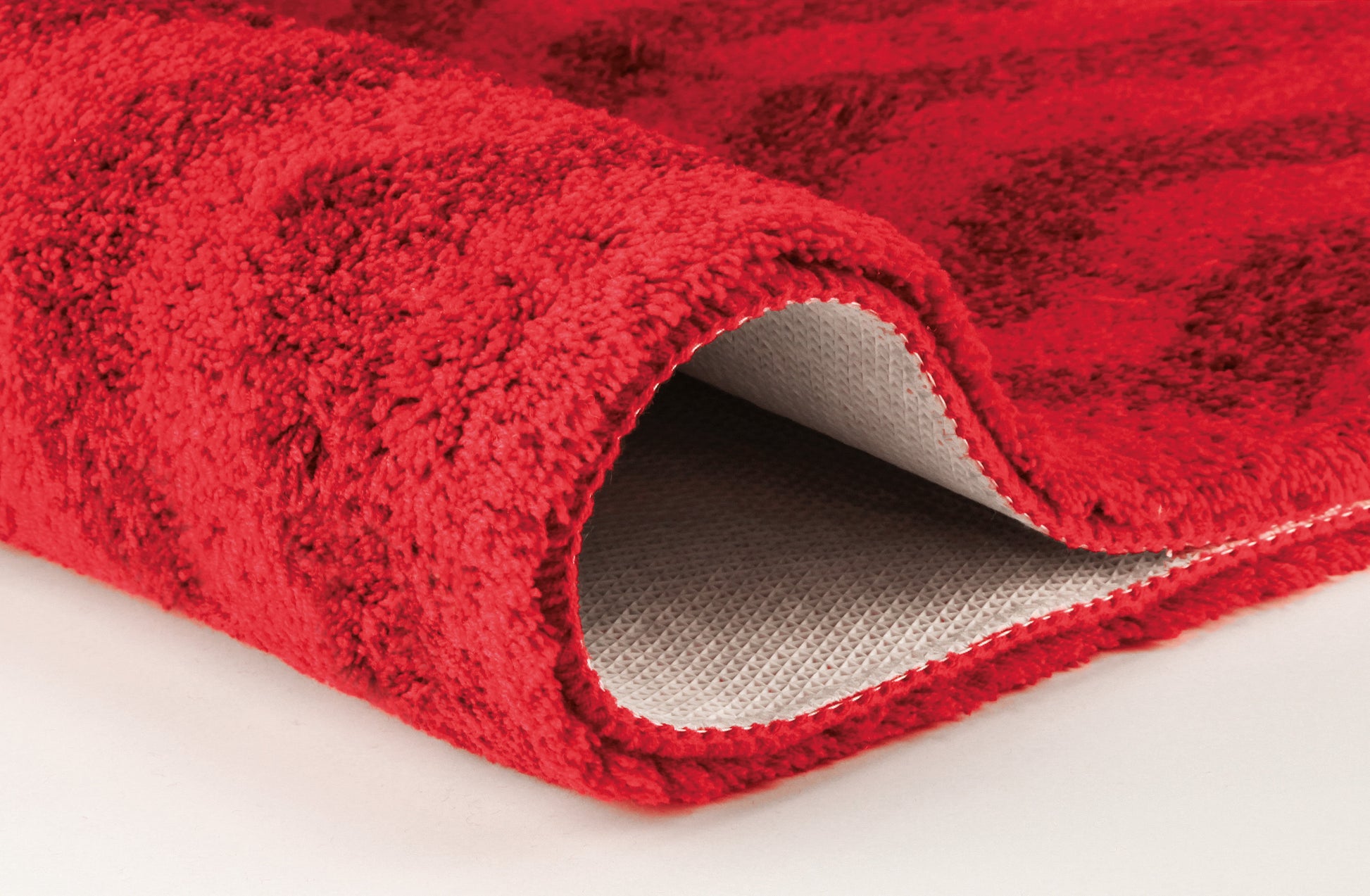 Nahaufnahme roter Badematte mit hochgeklappter Kante und Rücken sichtbar