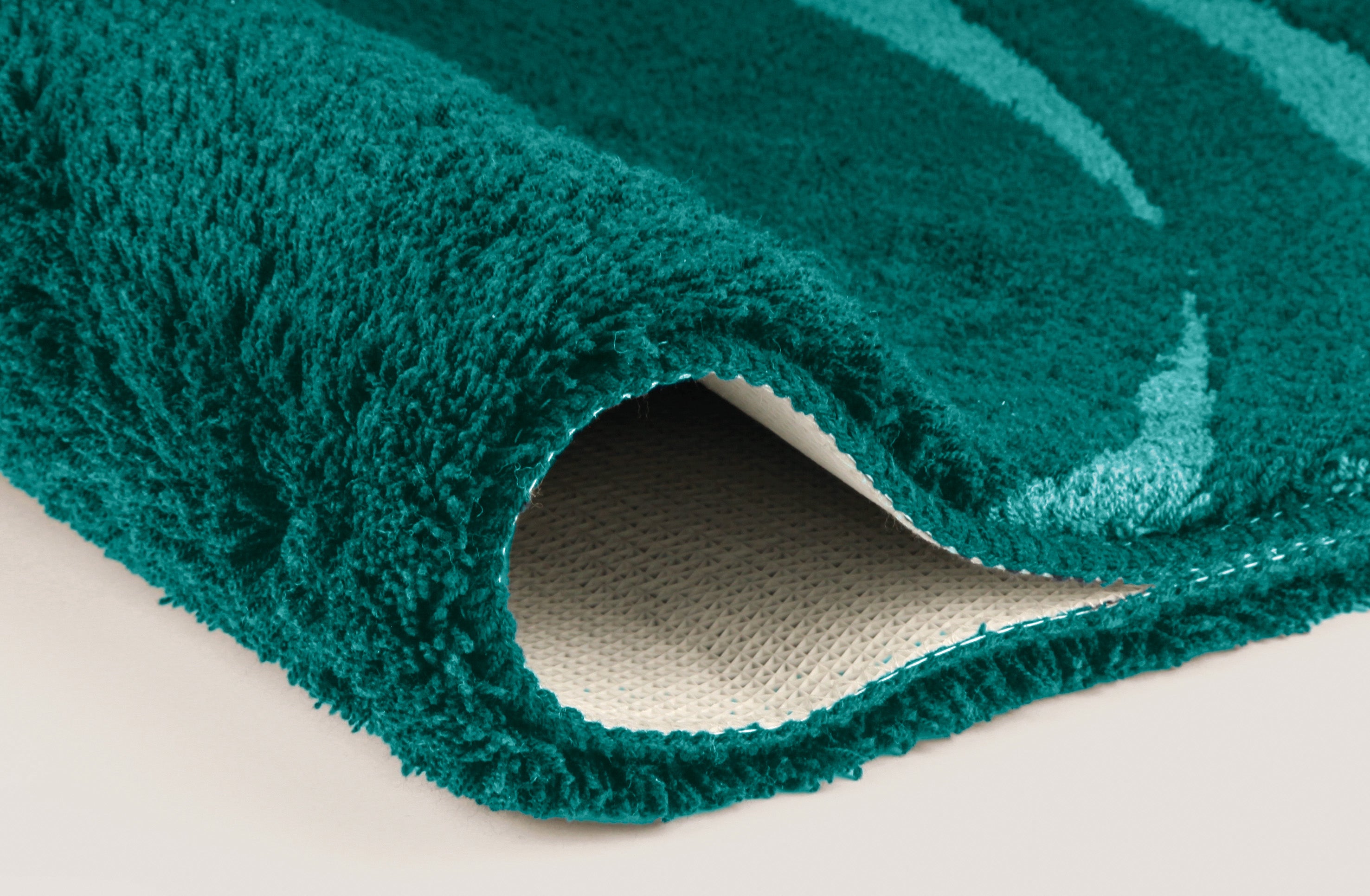 Nahaufnahme einer weichen, petrolfarbenen Badematte mit gepolstertem Rand