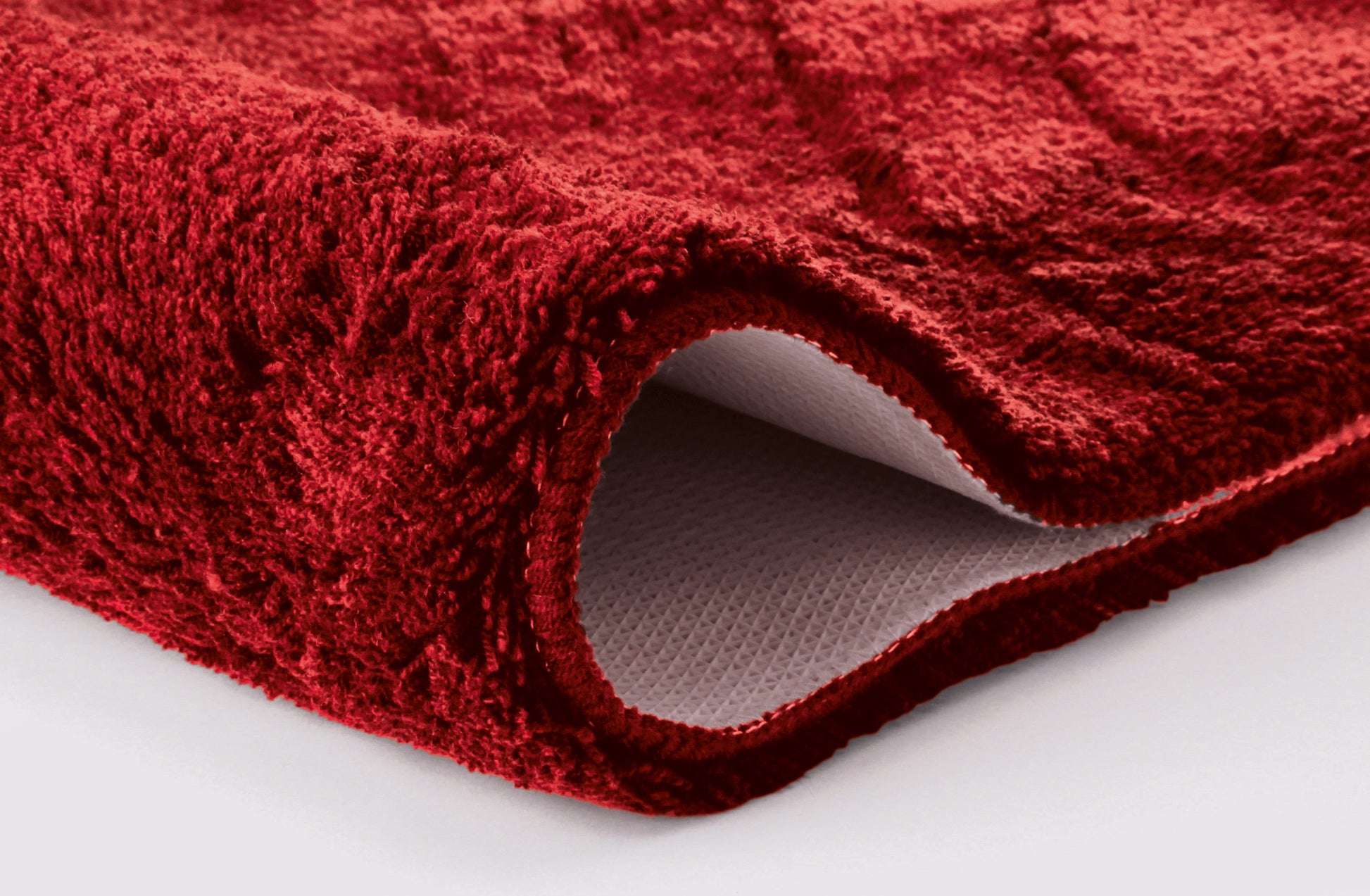 Nahaufnahme einer dicken, roten Badematte mit strukturierter Unterseite