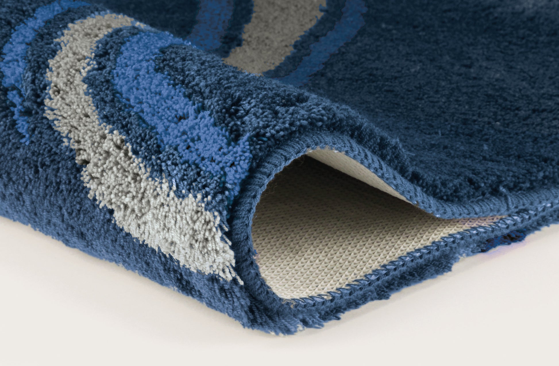 Nahaufnahme einer blauen Badematte mit grauen und hellblauen Wellen
