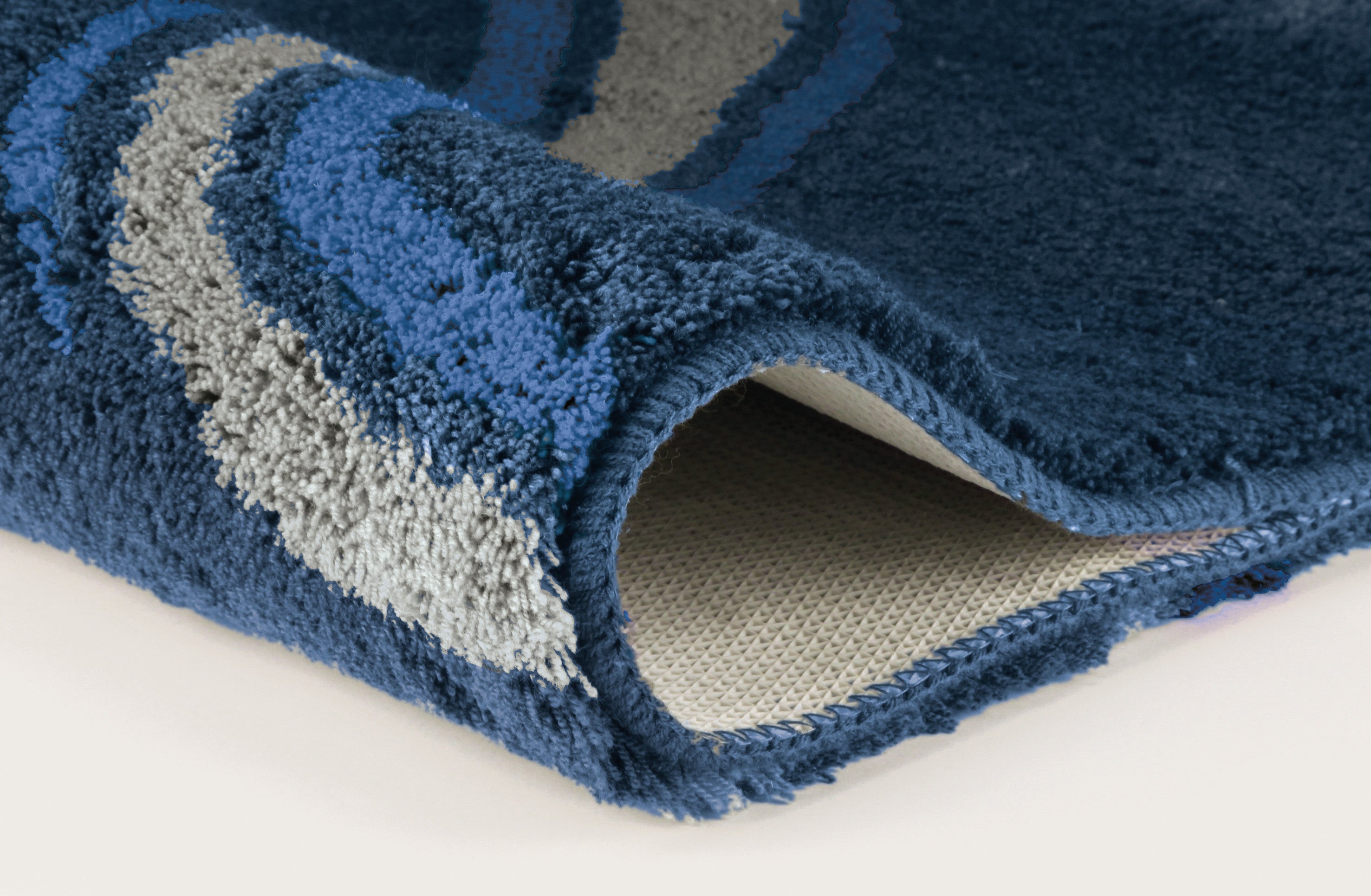Nahaufnahme einer blauen Badematte mit grauen und hellblauen Wellen