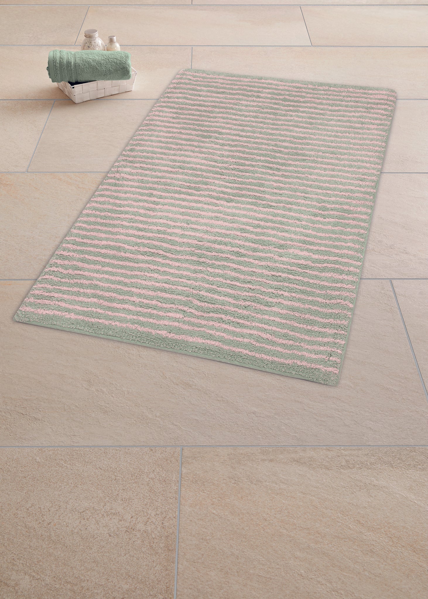 Gestreifter Badteppich in Rosa und Grau auf hellen Bodenfliesen liegt