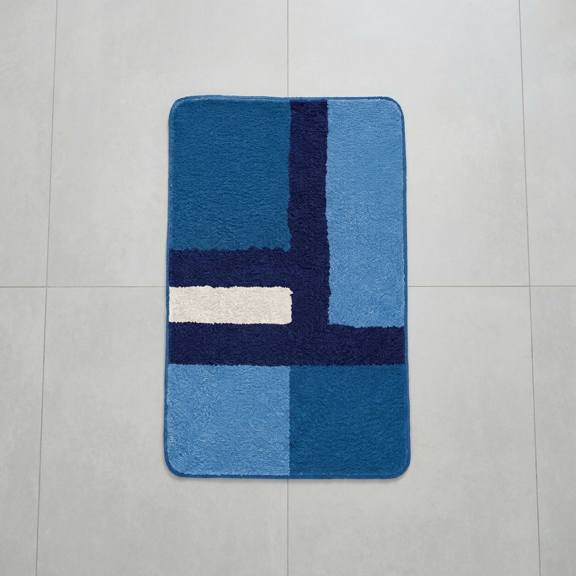 Rechteckiger blauer Badteppich mit geometrischem Muster auf Fliesen