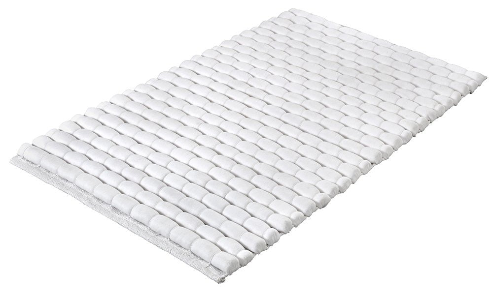 Weiße Badematte mit abgerundeter Kieseloptik auf hellem Untergrund