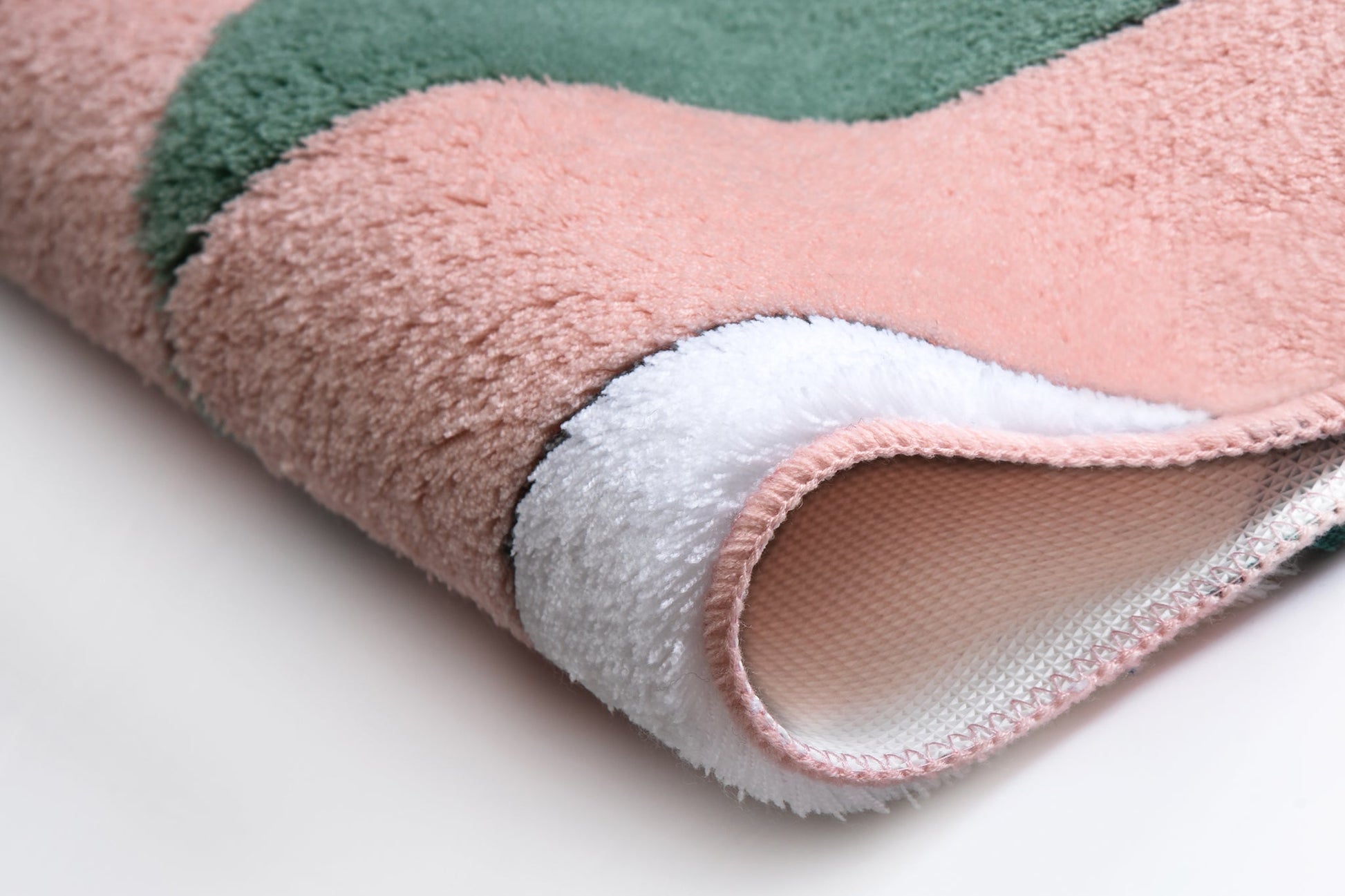 Nahaufnahme einer flauschigen Badematte in Rosa, Grün und Weiß