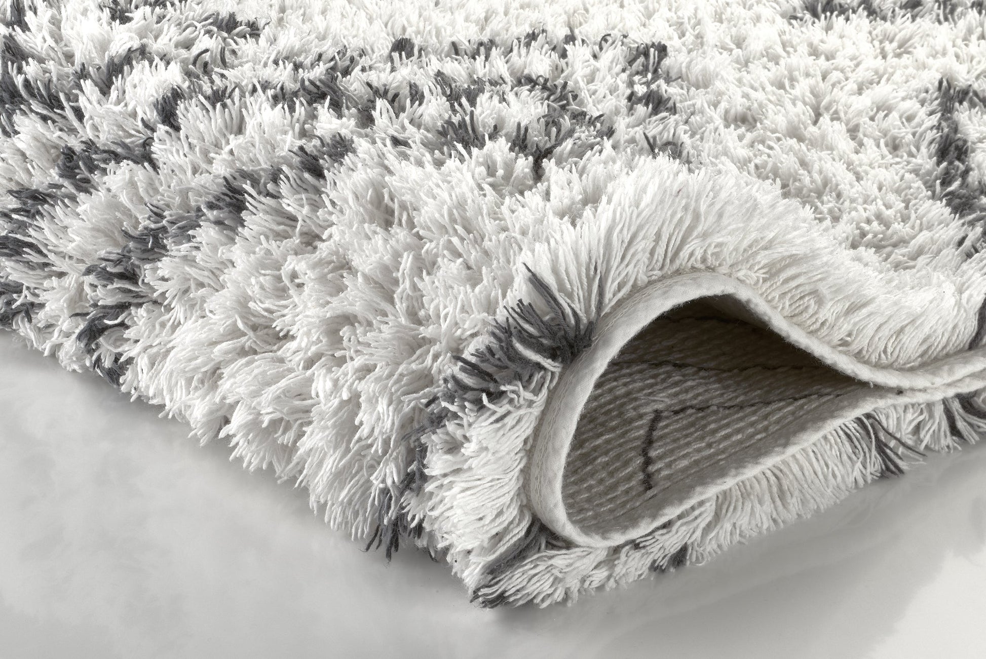 Nahaufnahme flauschige weiß-graue Badematte mit umgeschlagener Ecke