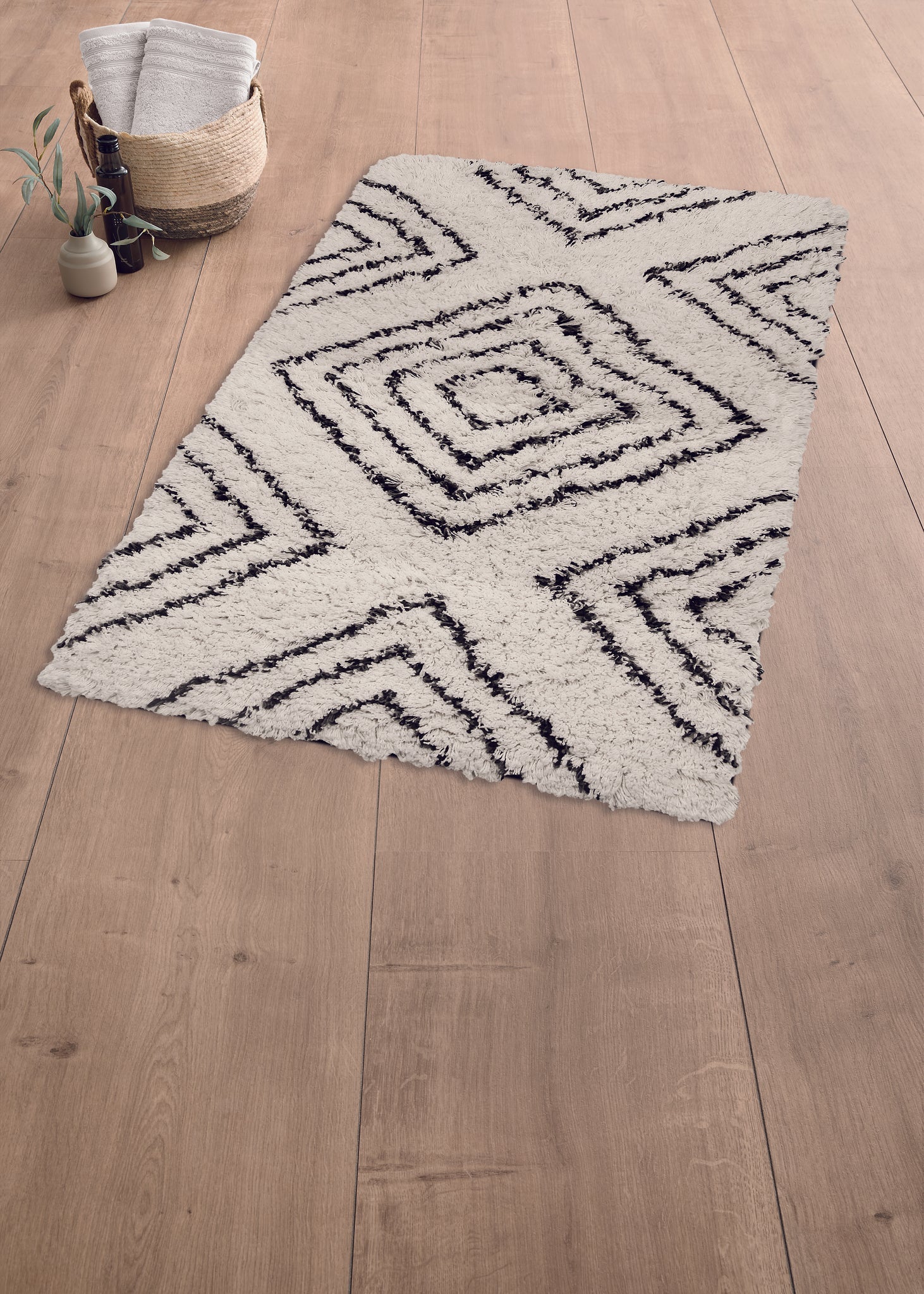 Weißer Hochflor-Teppich mit schwarzem Rautenmuster auf hellem Holzboden