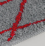 Graue Badematte mit rotem Rautenmuster, Kante und Textur nah gezeigt