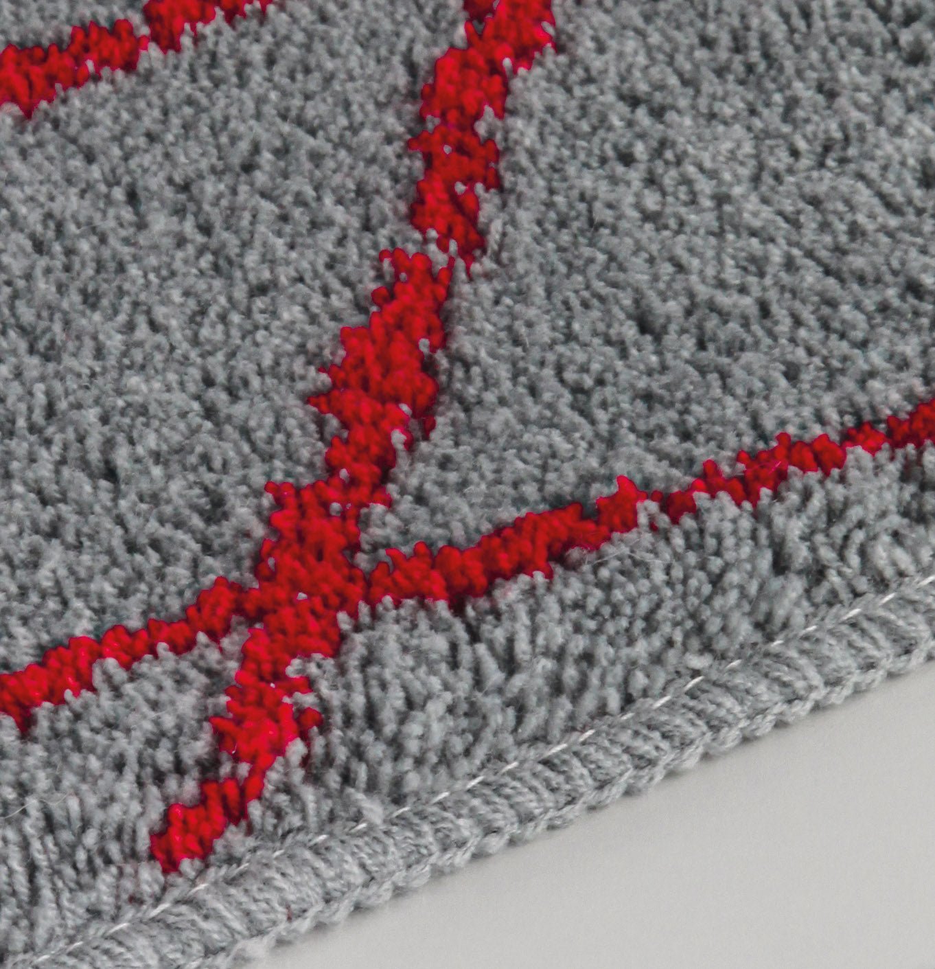 Badteppich BONDI Rubin 55 x 65 cm in Grau mit rotem Linienmuster in Nahaufnahme.
