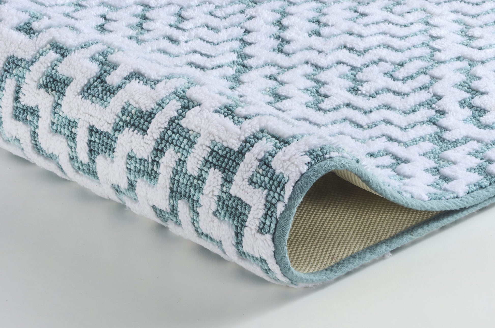 Weiche Badematte in Nahaufnahme mit weiß-türkisfarbenem Zickzackmuster