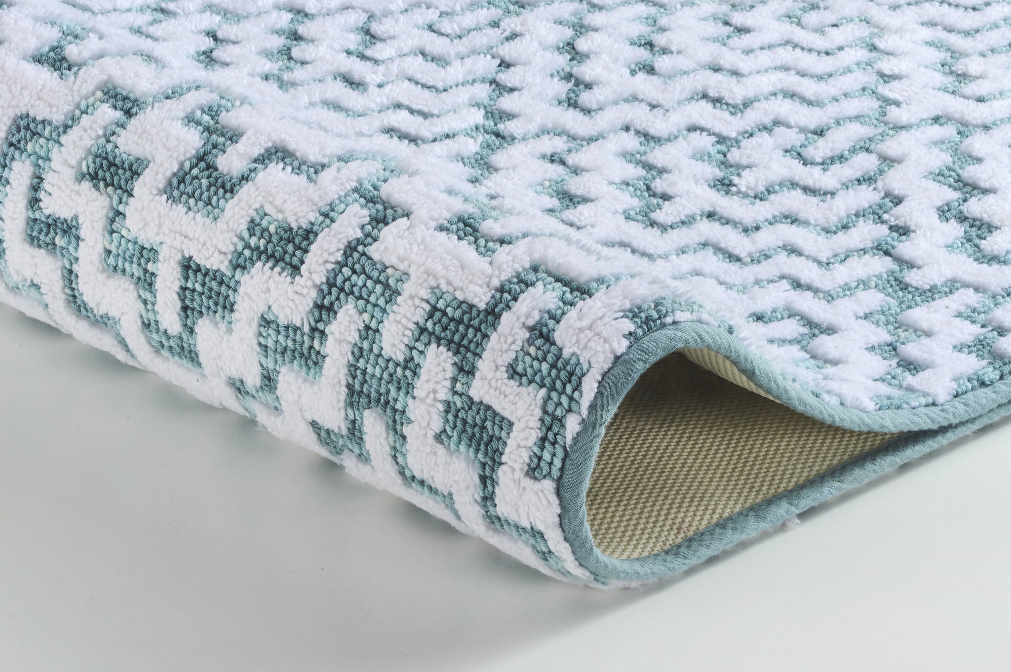 Weiche Badematte in Nahaufnahme mit weiß-türkisfarbenem Zickzackmuster