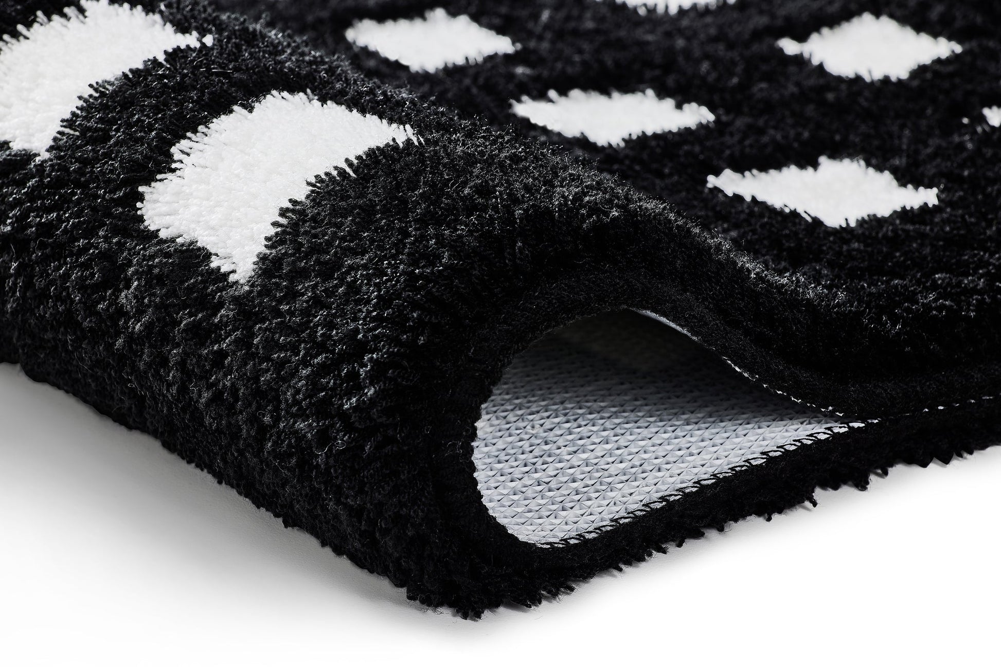 Nahaufnahme des Badteppichs BOXES in Schwarz-Weiß mit Kästchenmuster und sichtbarer Unterseite.