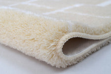 Nahaufnahme weicher cremefarbener Badteppich mit eingerollter Kante