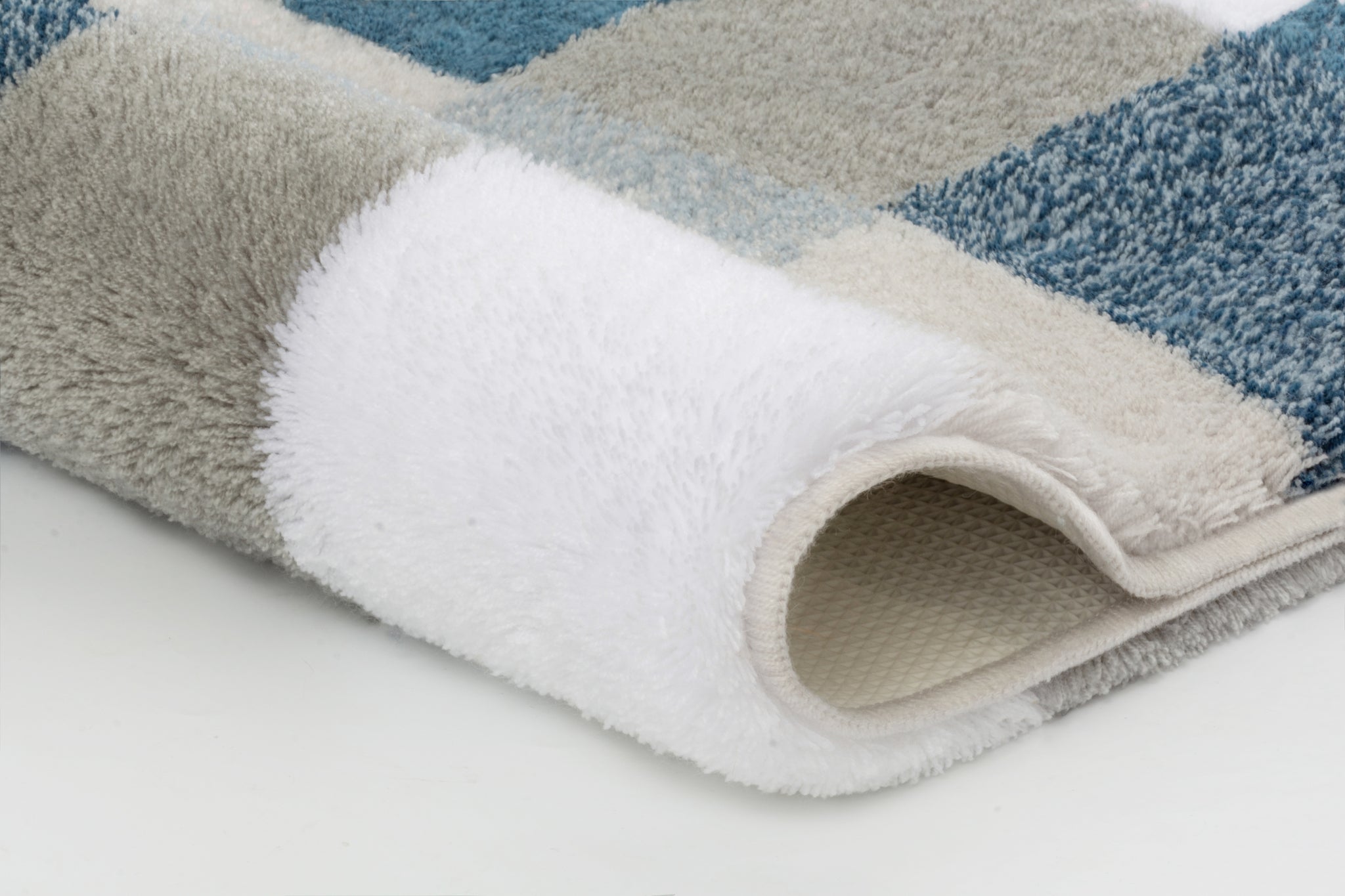 Badteppich CARO Mare 55 x 65 cm mit blau-grau kariertem Muster, Detailansicht der eingerollten Ecke.