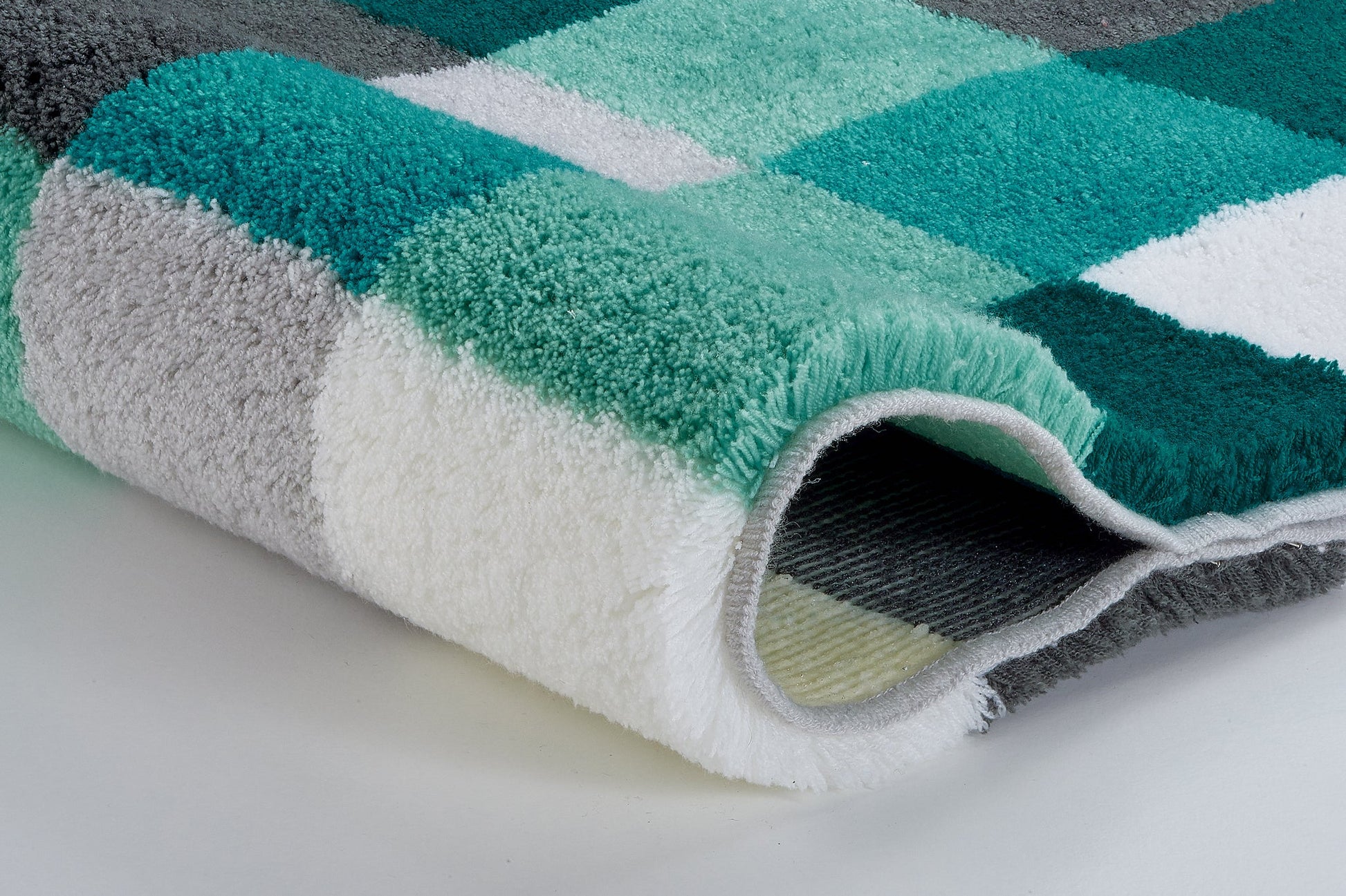 Badteppich CARO Petrol 85 x 150 cm mit kariertem Hochflorteppich in Petrol, Mint, Grau und Weiß in Nahaufnahme.