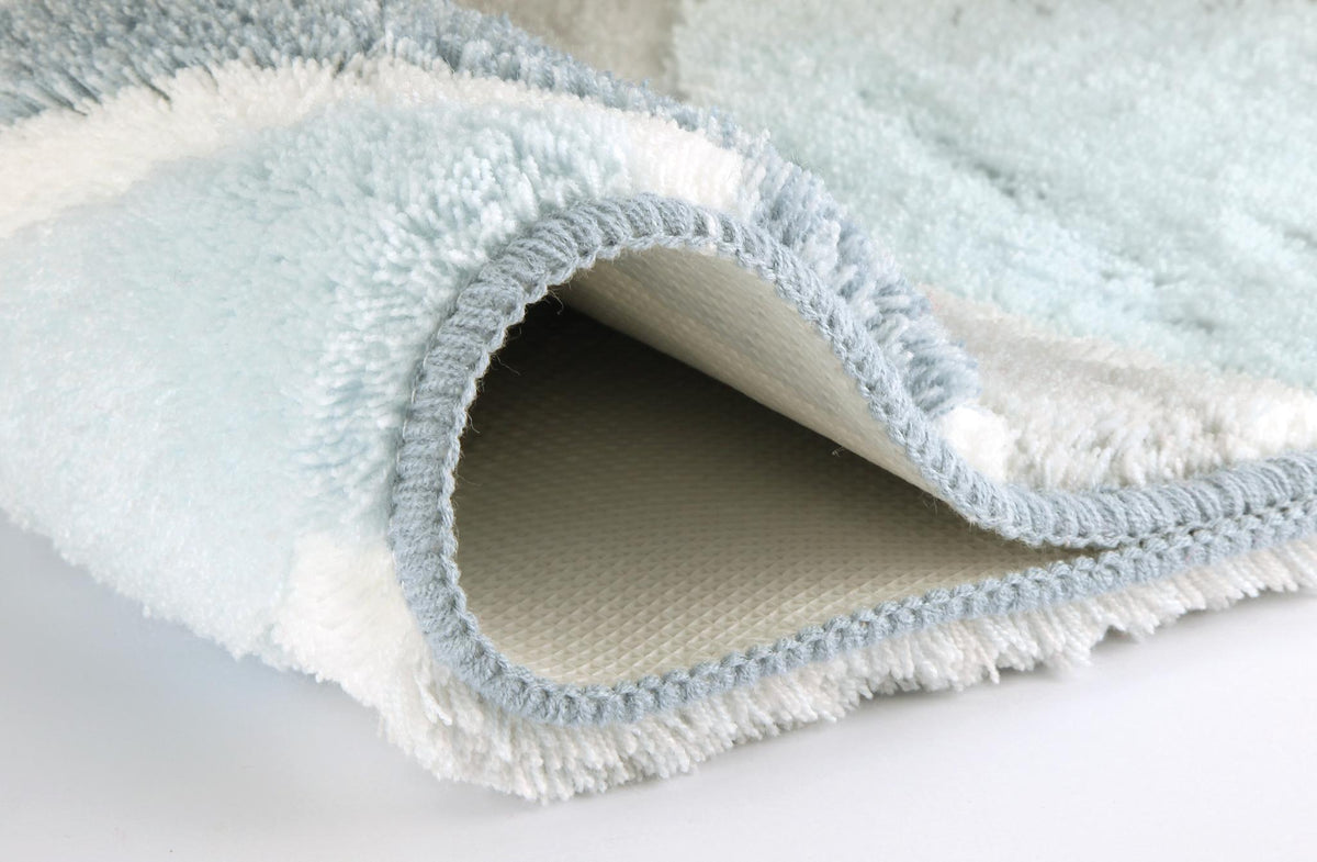 Weißer Badteppich mit hellblauer Umrandung und rutschfester Unterseite.