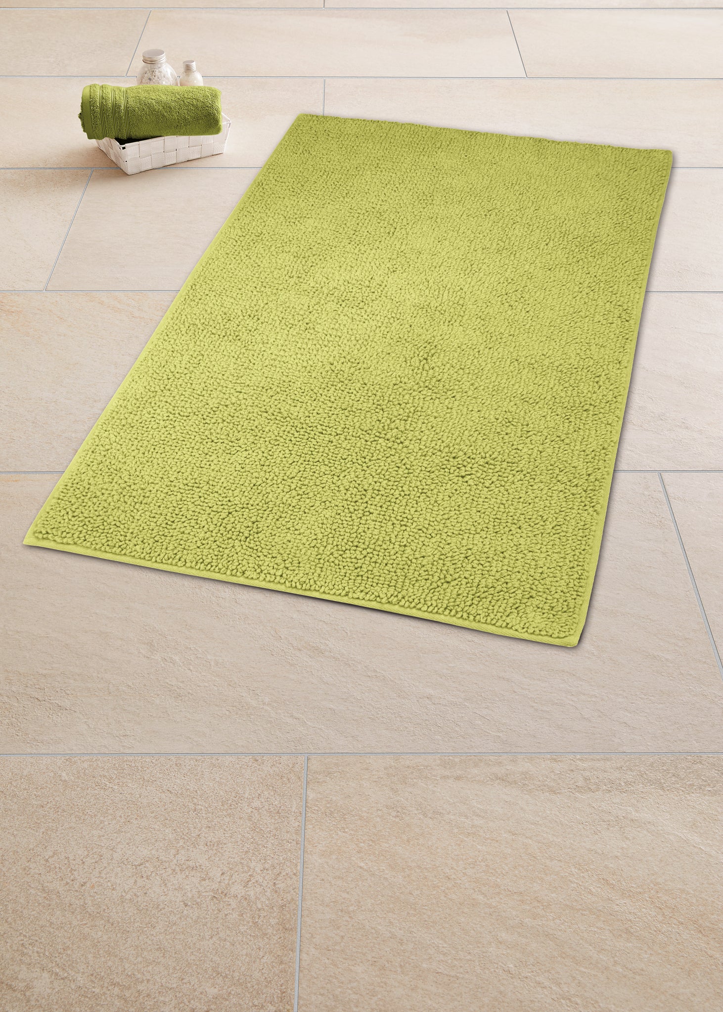 Grüner Badteppich CHRISSY Palme 65 x 115 cm liegt auf beige gefliesten Badezimmerboden.